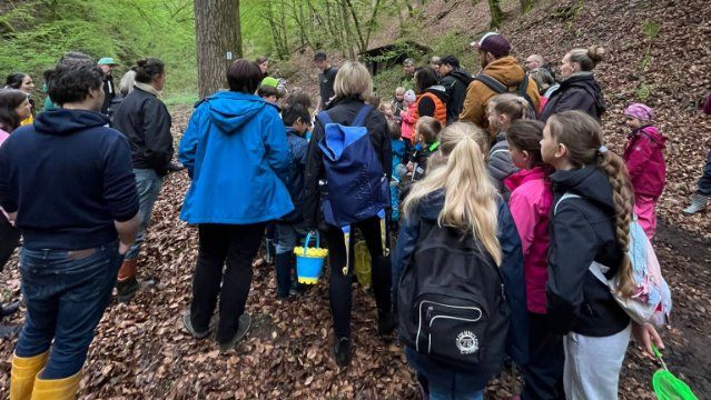 Kinder und  Erwachsene erforschen die Lebewesen im Bach