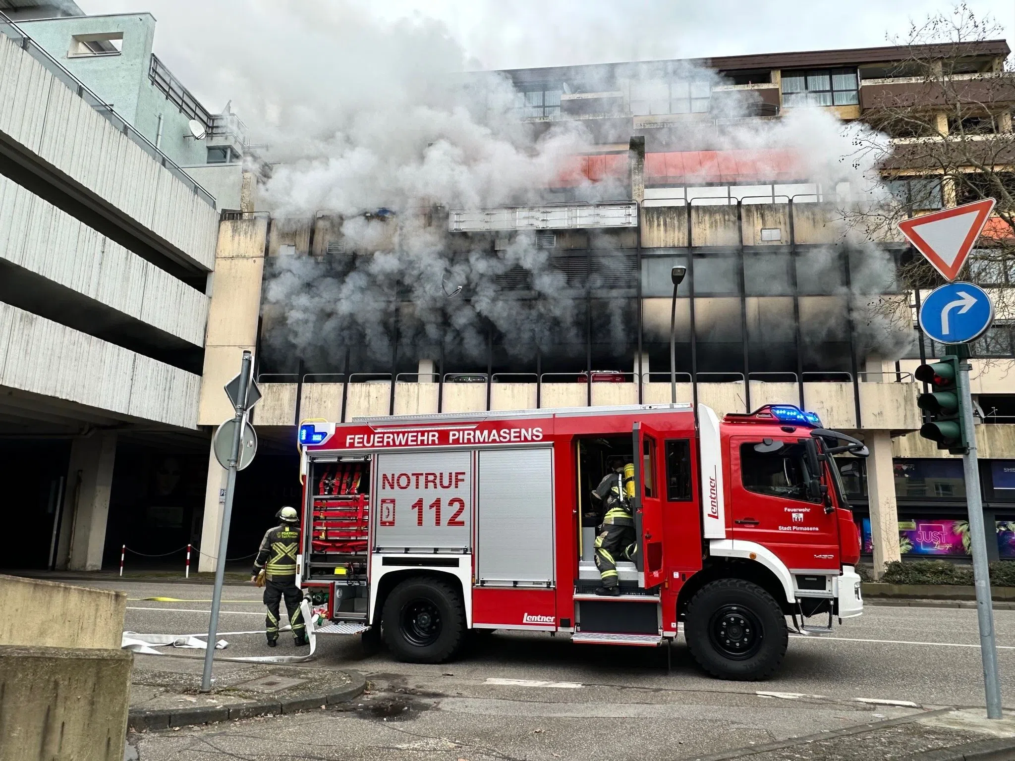 Feuerwehr mit Atemschutz löscht brennendes Auto im Parkhaus